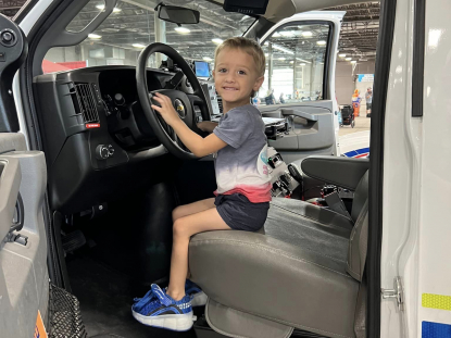 Kid posing on the driver's side of ambulance 